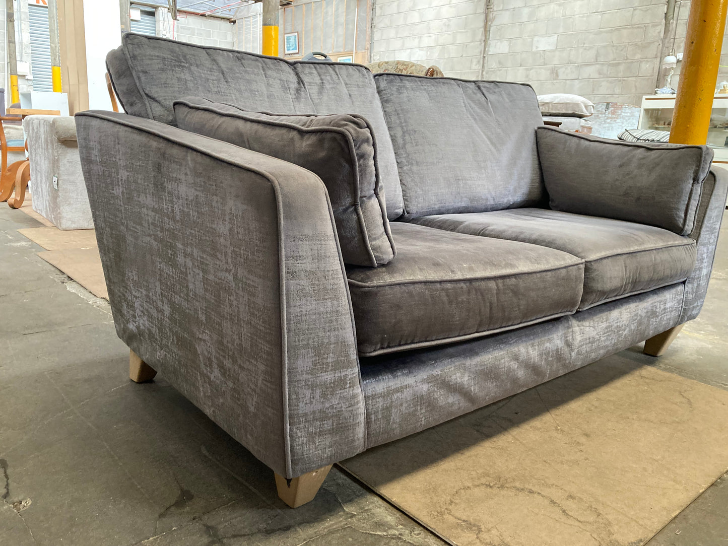 A large grey upholstered settee with cushions