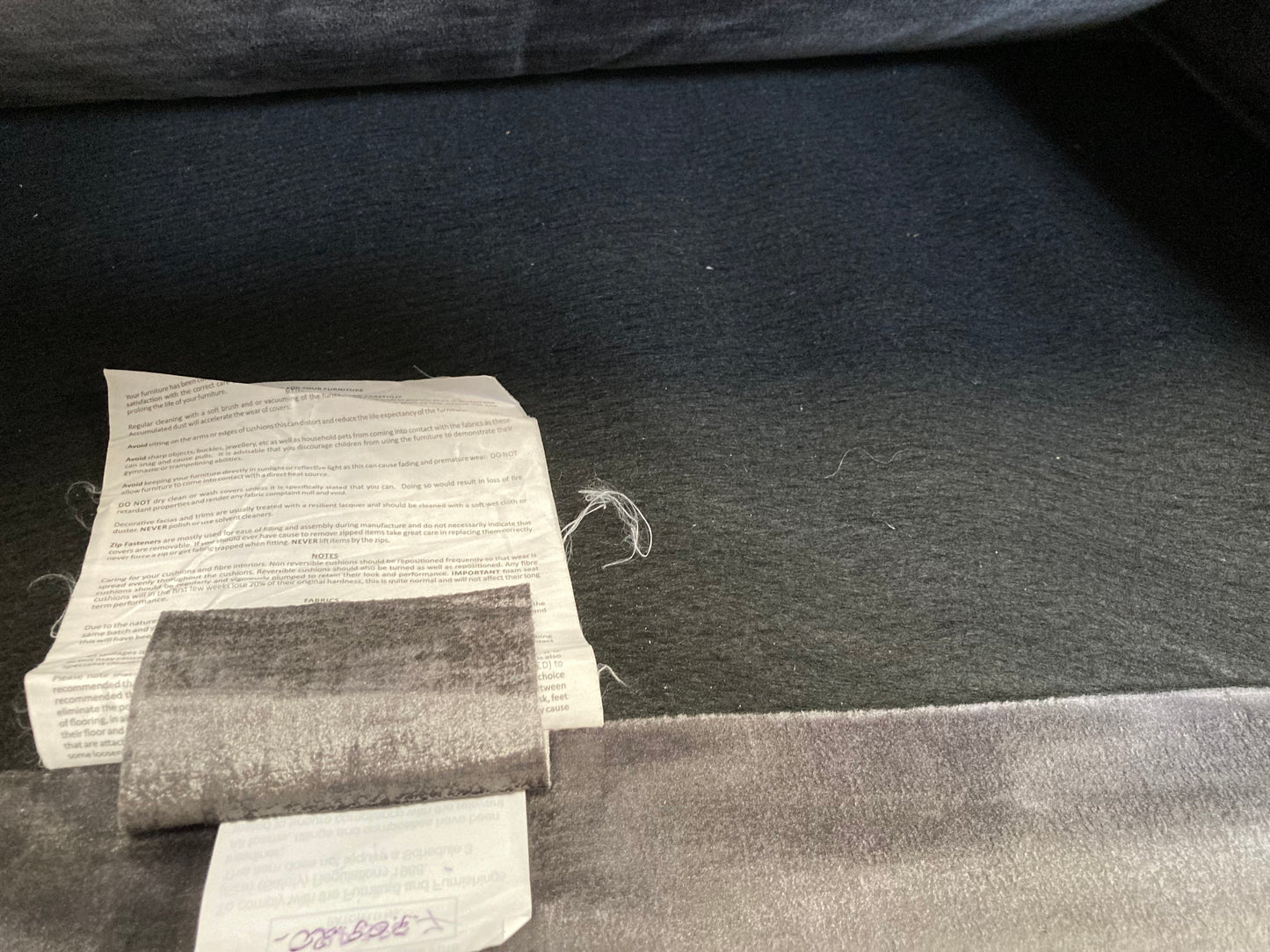 A large grey upholstered settee with cushions