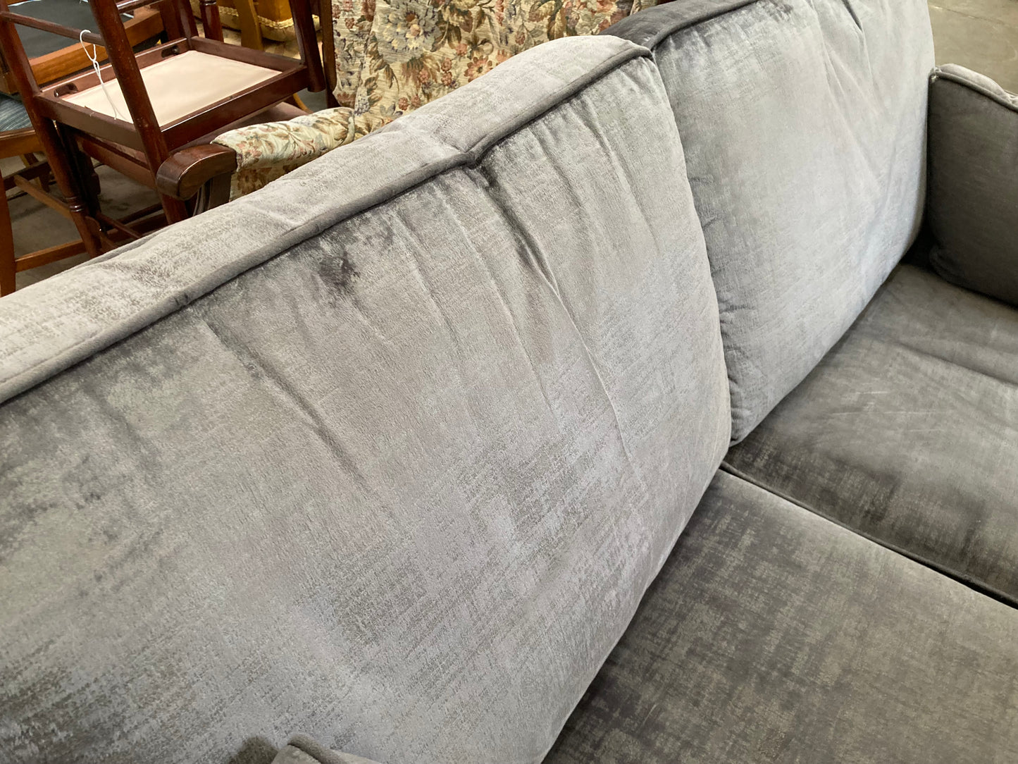 A large grey upholstered settee with cushions