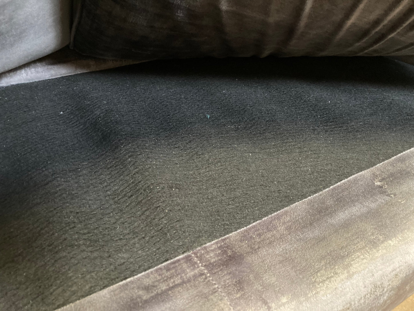A large grey upholstered settee with cushions