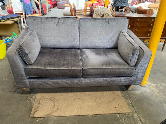 A large grey upholstered settee with cushions